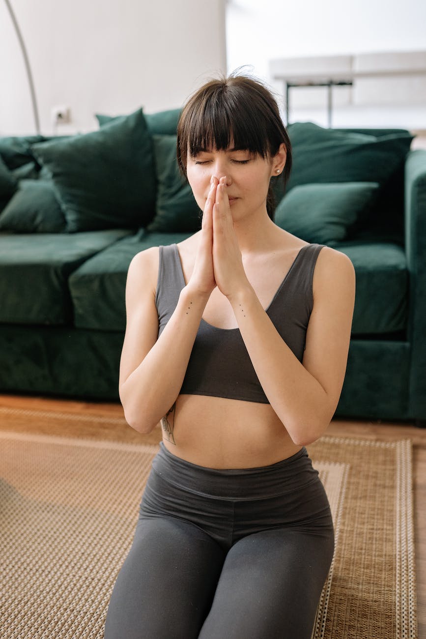 a woman in gray sports bra kneeling while meditating